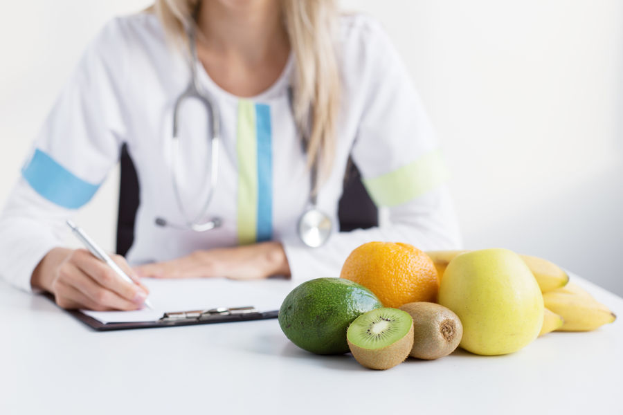 Dietitian doctor with healthy fruits on table
